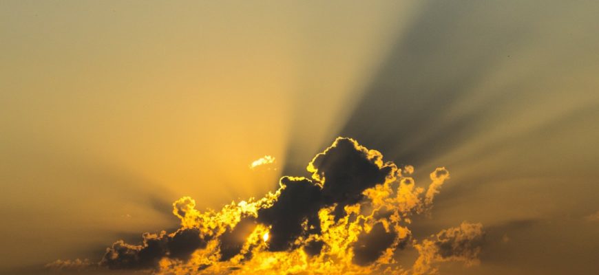 Sun rays protruding out behind dark clouds.
